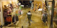 Una mujer achica el agua del interior de la tienda de deportes Olympus de la calle Padilla de Medina del Campo. / FRAN JIMÉNEZ